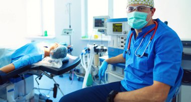 Ameliyat odasında arka planda erkek cerrah var..