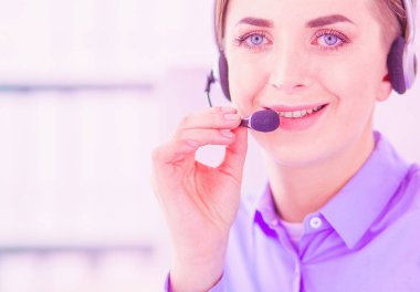 Ofisinde kulaklık takmış, telefon operatörü olarak çalışan ciddi ve güzel bir genç kadın..