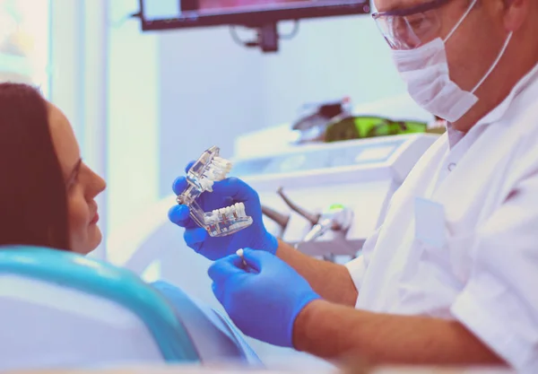 stock image Senior male dentist in dental office talking with female patient and preparing for treatment.