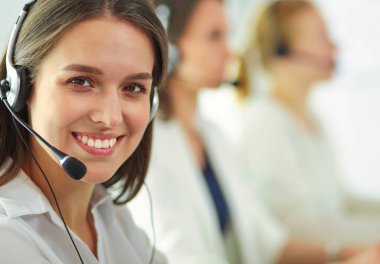 Ofisinde kulaklık ve bilgisayarla gülümseyen iş kadını ya da yardım hattı operatörü.