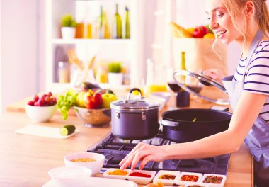 Evdeki mutfakta yemek pişiren güzel genç bir kadın..