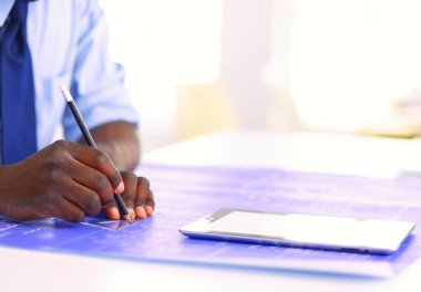 Ofiste bilgisayar ve planlarla çalışan Afrikalı Amerikalı bir mimar..