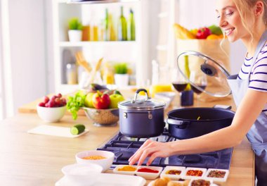 Evdeki mutfakta yemek pişiren güzel genç bir kadın..