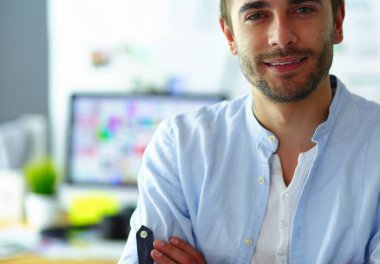 Dizüstü bilgisayar ve bilgisayar çalışırken önünde genç tasarımcı portresi. Onun mobil arka plan kullanarak Yardımcısı