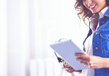 Gülümseyen kadın kahve içiyor ve kafede tablet kullanıyor.