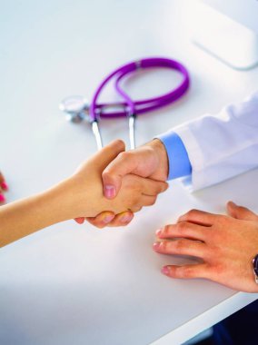 Doktor masadaki hastaya el sıkışıyor..