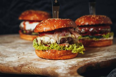 Üç sulu, peynirli sığır burger, marul ve domatesli, tadını çıkarmaya hazır..