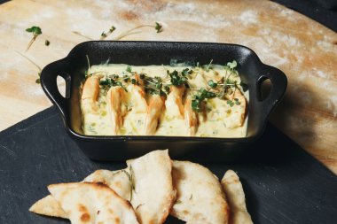 Lezzetli bir karışım ile izleyicileri cezbeden kremalı ve lezzetli bir sosla dolu bir kasenin üzerinde kabuklu bir ekmek yatıyor..