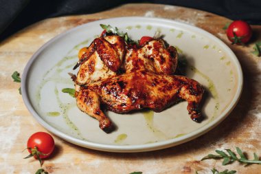 Lezzetli ızgara tavuk, sulu domatesler ve taze otlarla dolu bir tabak lezzetli ve iştah açıcı bir yemek yaratıyor..