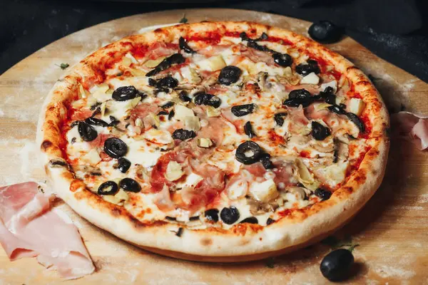 Kırsal ahşap bir tahtanın üzerinde çeşitli zeytinli bir gurme pizza..