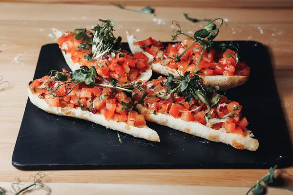 Lezzetli domatesler ve mis kokulu otlarla dolu taze yapılmış bruschetta dolu bir tabak. Canlı renkleri ve lezzetli aromasıyla seyirciyi cezbediyor..