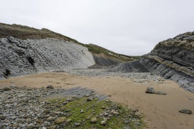 Pedruquios sahilindeki kıyı erozyonu, kayalıklardaki tortulu kayalar ve kayalıklar ve Cantabrian Denizi, Costa Quebrada, Liencres, Kuzey İspanya kıyılarındaki dalgalar tarafından aşınan araziler.