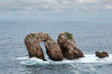 Urro del Manzano (ayrıca Canto del Diablo veya La Puerta olarak da bilinir), Cantabrian Denizi 'nin dalga hareketi ile oyulmuş doğal kemer köprüsü. Urros de Liencres, Costa Quebrada, Cantabria, Kuzey İspanya