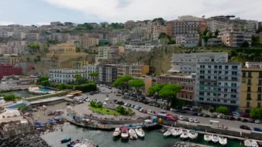 Turist bölgesindeki deniz manzarası. Deniz kıyısının yukarısındaki yamaçlarda büyük binalar ve tarihi saraylar. Napoli, İtalya.