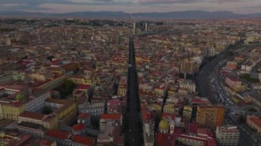 Şehir merkezindeki uzun düz sokağın üzerinde ilerliyorlar. Alacakaranlıktaki büyük şehrin havadan panoramik görüntüsü. Napoli, İtalya.