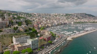 Deniz kıyısındaki tarihi şehrin hava panoramik manzarası. Turistik bölgelerdeki büyük saraylar ve otel binaları. Teknelerle marinada dolaş. Napoli, İtalya.