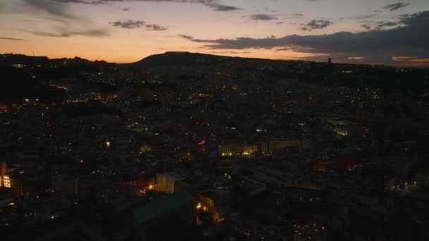 前方の夕方の都市の上を飛ぶ 都市のバラとロマンチックなカラフルな夕暮れの空に照らされた建物や通り ナポリ イタリア — ストック動画