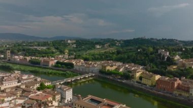 İleri uçaklar şehrin üzerinde ve Arno nehrinin üzerinde köprü oluşturur. Yeşil ağaçlı bahçelerin havadan görünüşü. Floransa, İtalya.