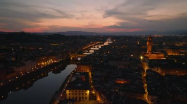 Akşam şehrinin üzerinden uç. Arno nehrinin rengarenk alacakaranlık gökyüzünü yansıtması. Tarihi manzaranın havadan görünüşü Ponte Vecchio. Floransa, İtalya.