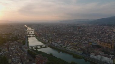Eski kasabadaki Arno nehri boyunca uzanan köprülerin hava görüntüsü. Gün batımında ünlü simgeleri olan şehir manzarası. Floransa, İtalya.