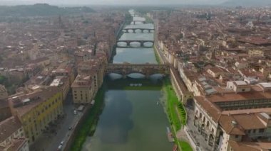 Eski kasabadaki Arno nehrinin üzerinde ilerliyorlar. Tarihsel turist eğlencesi Ponte Vecchio. Eğim puslu havada şehir manzarasını gözler önüne serer. Floransa, İtalya.