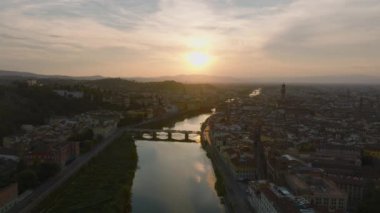 Arno nehri üzerindeki köprülerin romantik, renkli günbatımına karşı hava görüntülerini alıyor. Ünlü turistik yerleri olan eski bir kasaba. Floransa, İtalya.