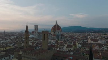 Alacakaranlıkta eski kasabadaki tarihi kulelerin etrafında ileriye doğru uçarlar. Meşhur Duomo di Firenze 'ye doğru gidiyor. Floransa, İtalya.