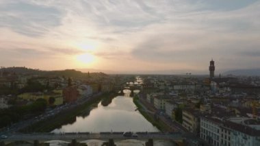 İleri, Arno nehri ve köprüleri üzerinde uçar. Güneşin batışına karşı eski şehrin havadan romantik manzarası. Floransa, İtalya.