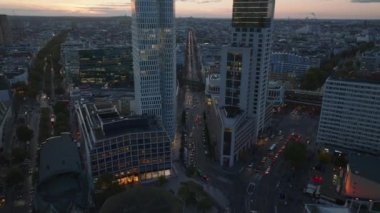 Alacakaranlıkta şehir merkezindeki modern yüksek binalar arasında ileriye doğru uçar. Charlottenburg Mahallesi, Berlin, Almanya.