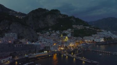 Deniz kenarındaki tarihi kasabanın akşam görüntüleri yüksek kayalıklarla çevrili. Sokak lambaları ve aydınlatılmış katedral. Amalfi, İtalya.