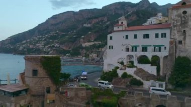 Turistik bölgede kıyı yolu üzerinde ilerliyorlar. Arabalar ve ambulans keskin virajdan geçiyor. Deniz kıyısındaki eski kasabayı gözler önüne seriyor. Amalfi, İtalya.