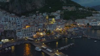 Akşam kasabasının hava kaydırak ve pan görüntüleri. Tarihi şehir merkezinde ışıklandırılmış rıhtım ve simgeler. Amalfi, İtalya.