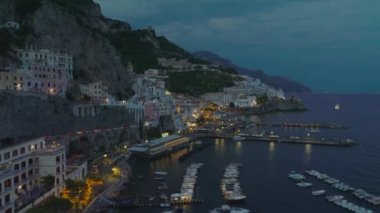 Akşamları tarihi şehirde deniz kıyısında ilerliyorlar. Yat limanında demirlemiş bir sürü tekne. Amalfi, İtalya.