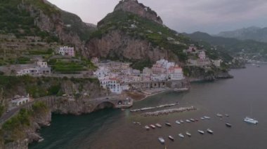 Küçük bir kasabada yüksek kayalıklar arasında sıkışan binaların hava kaydırak ve pan görüntüleri. Amalfi, İtalya.