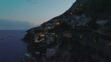 Deniz kıyısının yukarısındaki yamaçta apartman ve yol trafiğinin akşam çekimleri. Amalfi, İtalya.