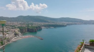 Korkuluklarda dikilen ve deniz körfezindeki seyahat noktalarının güzel manzarasına hayran olan bir grup turistin üzerinden uçmak. Amalfi, İtalya.