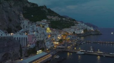 Deniz kıyısının havadan görünüşü ve akşam popüler turizm beldelerindeki işaretler. Aydınlatılmış tarihi binalar. Amalfi, İtalya.
