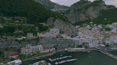 Deniz kıyısındaki yüksek kaya duvarı boyunca inşa edilmiş evlerin hava görüntüleri. Seyahat yerindeki turistik yerler. Amalfi, İtalya.