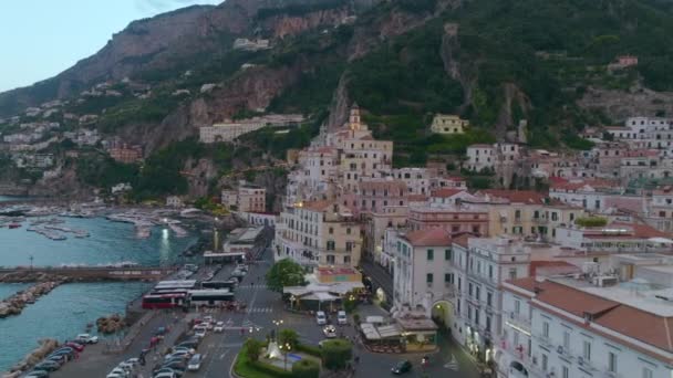 旧市街の忙しいウォーターフロントと歴史的な建物の空中スライドとパンショット マリーナでのボートと背景に水の上に構築します Amalfi イタリア — ストック動画