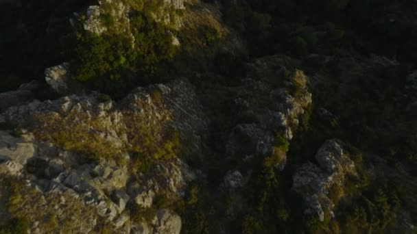 前方の岩や緑の植生の上に低い太陽によって点灯飛ぶ 自然シーンの高角度ビューでは 明らかに道路巻き Amalfi イタリア — ストック動画