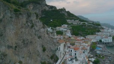 Yüksek kaya duvarı boyunca binaların sinematik görüntüleri. Katedral 'le tarihi bir kasabanın ifşası. Amalfi, İtalya.