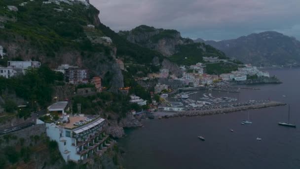 黄昏时分 沿着海滨的旅游胜地向后飞去 高高在上的陡峭岩石斜坡上的建筑物 意大利阿马尔菲 — 图库视频影像