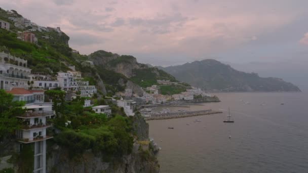 海岸の上の急な岩の斜面に豪華なアパートの建物の高床式の映像 海辺の風景の中に歴史的な町 Amalfi イタリア — ストック動画