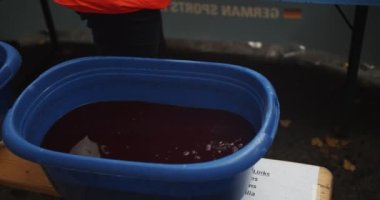Koyu kırmızı içecekle büyük plastik bir kap yakın çekim. Personel bardaklara su dolduruyor. Maraton koşu yarışı, Berlin, Almanya.