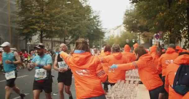 Členové Posádky Oranžových Bundách Poskytující Vodu Běžců Sportovní Událost Ulicích — Stock video