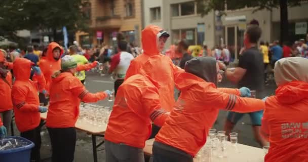 Miembros Tripulación Vibrantes Chaquetas Naranjas Que Ofrecen Agua Los Atletas — Vídeos de Stock