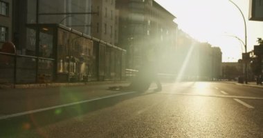 Adam sabah spor müsabakasından önce şehir sokaklarında zamanlama ekipmanı kuruyor. Bisikletli geziyor. Parlak güneş ışığına karşı görüş. Maraton koşu yarışı, Berlin, Almanya.