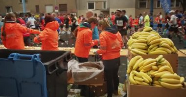 Ekip üyeleri içecekleri hazırlıyor ve sporculara taze meyve sunuyorlar. Maraton koşu yarışı, Berlin, Almanya.