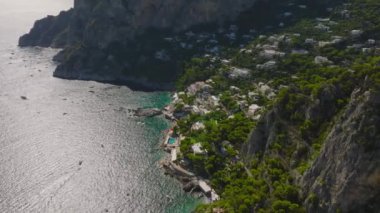 Yüksek kaya duvarları olan engebeli deniz kıyılarıyla çevrili turistik bir yer. Capri, Campania, İtalya.