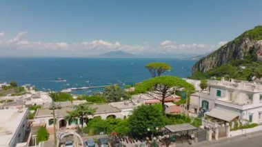 Yaz tatilinde şehrin caddelerinin ve binaların üzerinden ileriye doğru uçarlar. Mavi deniz ve Vezüv mesafesi. Capri, Campania, İtalya.